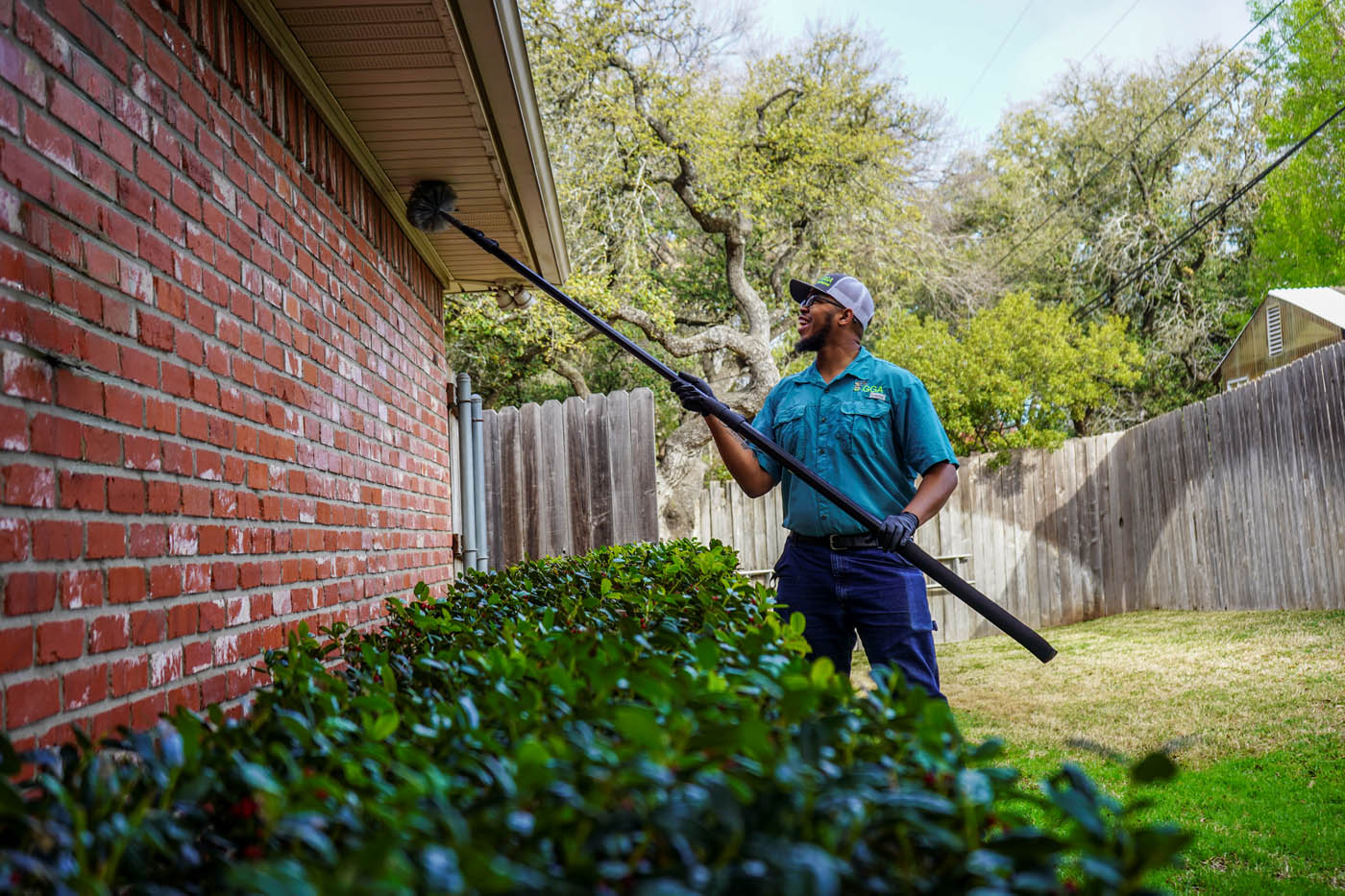 A technician from GGA Pest Management cleaning the exterior of a home after a critter control visit.