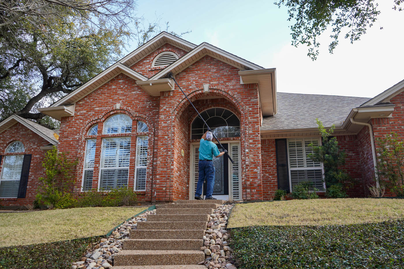 A GGA Pest Management technician inspecting a brick red house, contact us for a residential exterminator in Temple, TX.