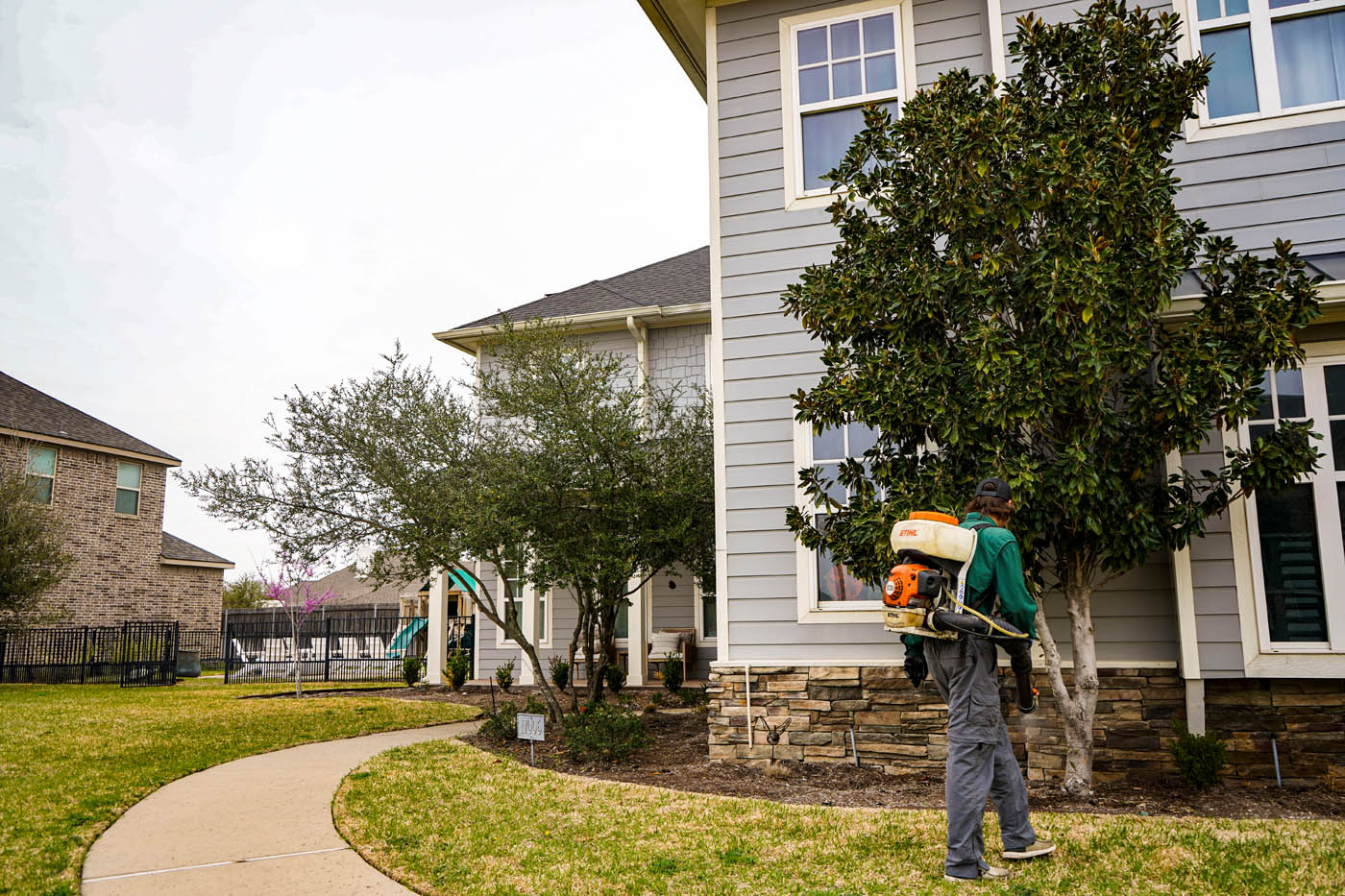 GGA Pest Management walking around a residential home spraying for pest management in Hillsboro, TX.