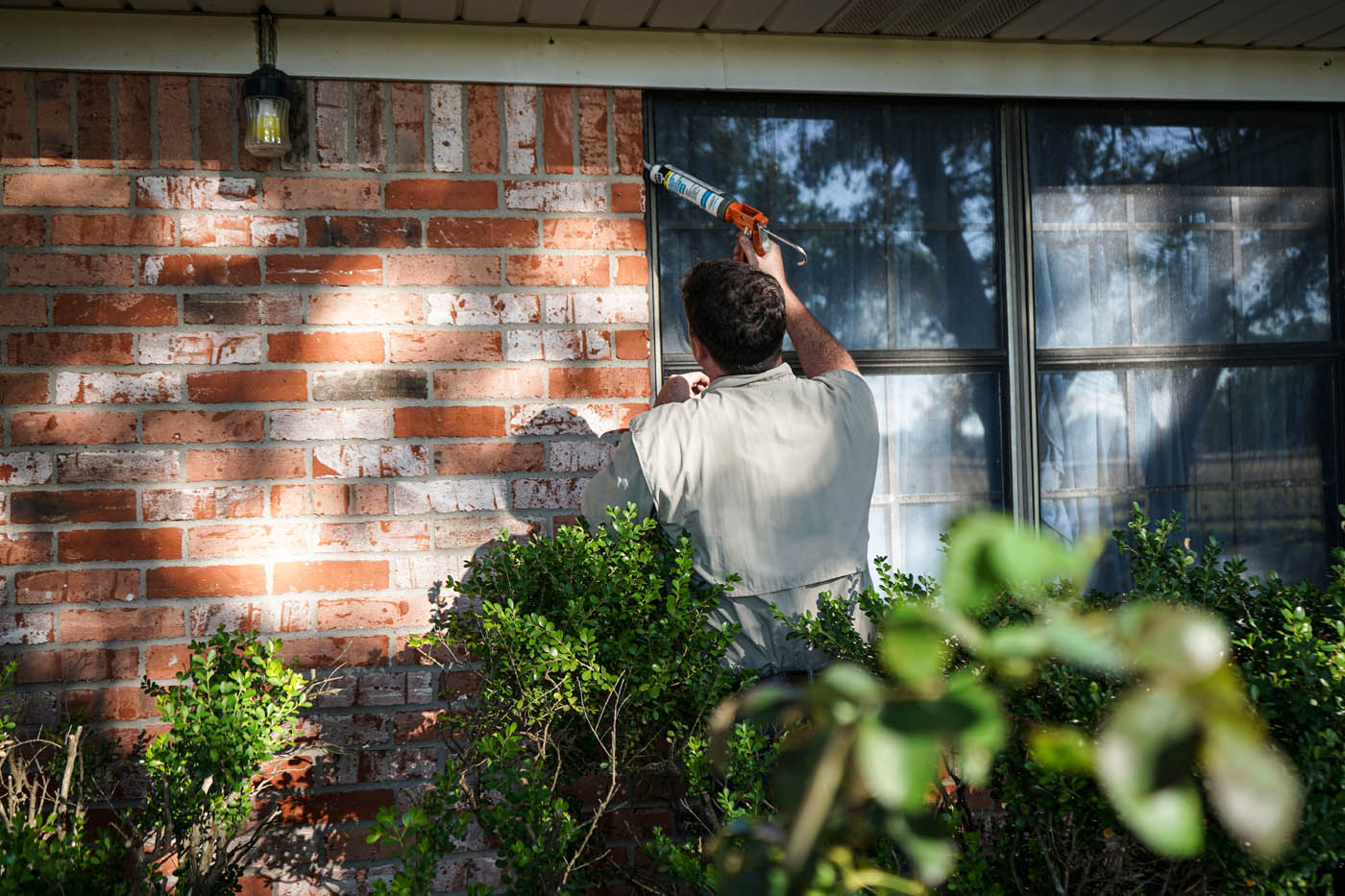 A GGA Pest Management Temple technician sealing entry points for rodents outside a home.